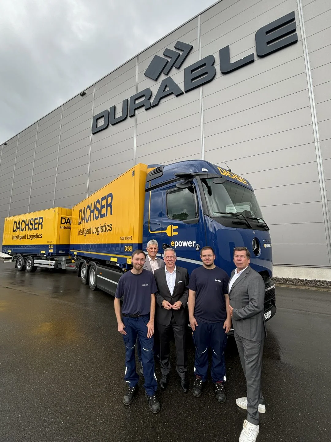 Mitarbeitende von Durable und DACHSER Dortmund mit einem E-Lkw im Hintergrund auf dem Betriebsgelände von Durable.