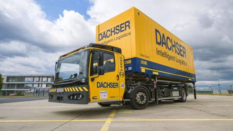 Ein elektrisch angetriebenes Wechselbrückenfahrzeug, auch Hochumsetzer genannt, steht auf dem Beitriebshof der Niederlassung Erlensee, beladen mit einer Wechselbrücke mit DACHSER Aufschrift.