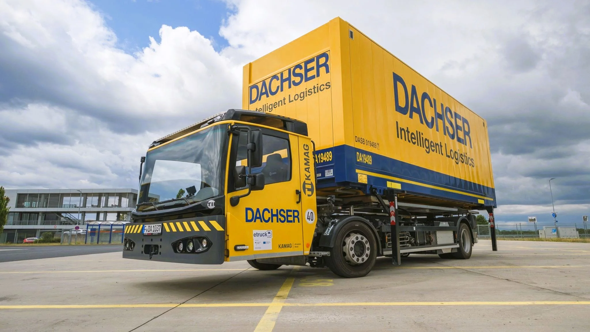 Ein elektrisch angetriebenes Wechselbrückenfahrzeug, auch Hochumsetzer genannt, steht auf dem Beitriebshof der Niederlassung Erlensee, beladen mit einer Wechselbrücke mit DACHSER Aufschrift.