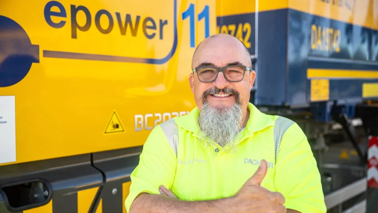 Alexander Sontheim, Fahrertrainer bei der DACHSER Driver and Truck Fleet Service GmbH steht vor einem E-Lkw und zeigt den Daumen nach oben