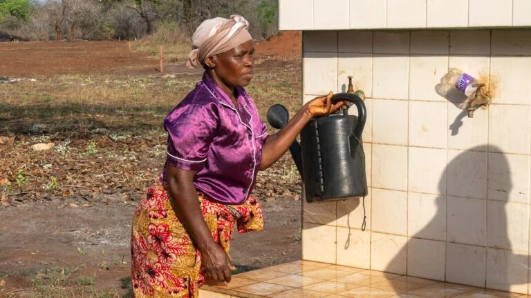 2025-10-30 Mozambique Klimaschutz terre des hommes-207 Eine Frau in einem Dorf in Mosambik holt Wasser an einer Brunnenanlage