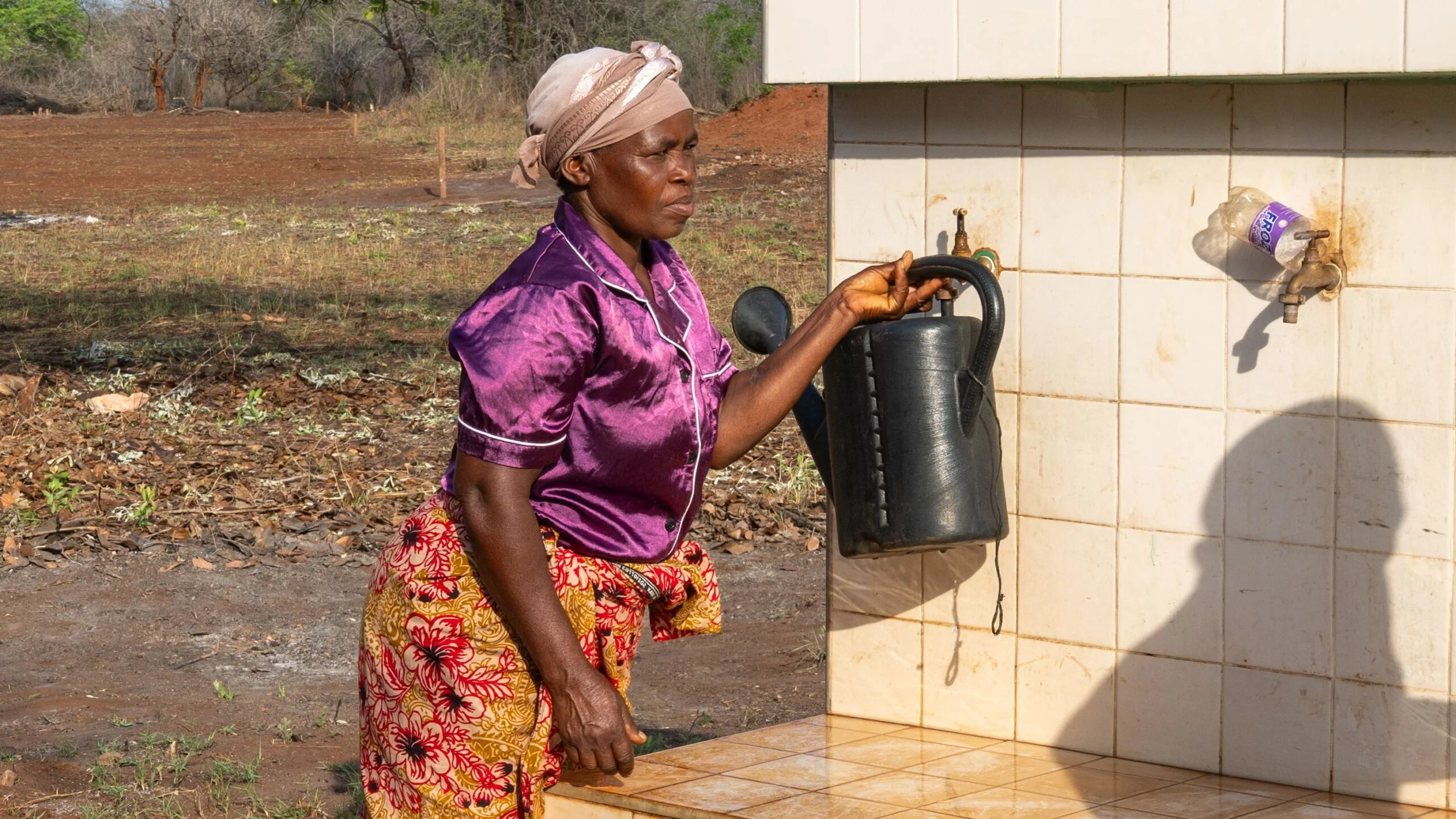 Eine Frau in einem Dorf in Mosambik holt Wasser an einer Brunnenanlage