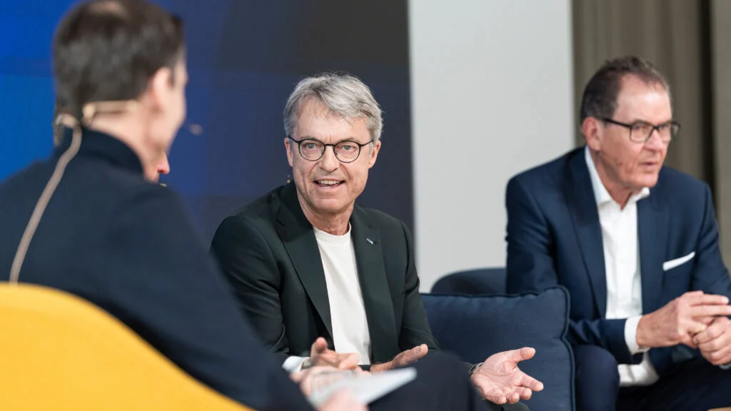 Bernhard Simon spricht auf einem Sofa auf der Bühne