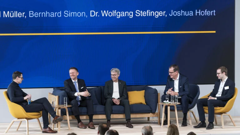 Vertreter aus Politik, Dachser und Terre des Hommes sitzen auf einem Sofa und Stühlen auf der Bühne und unterhalten sich 