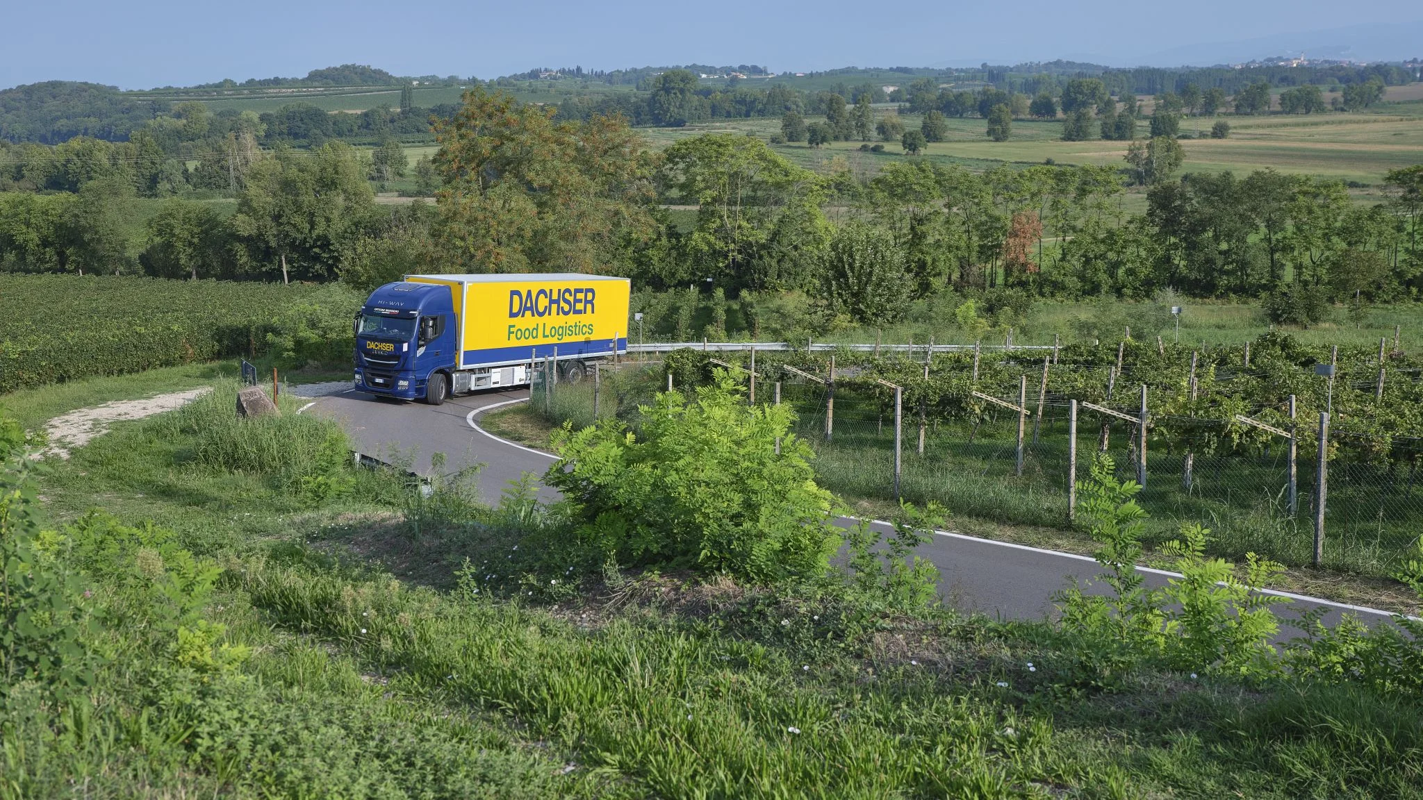 DGI_004555 Ein Lkw mit Food Logistics Aufschrift fährt durch eine grüne Landschaft.