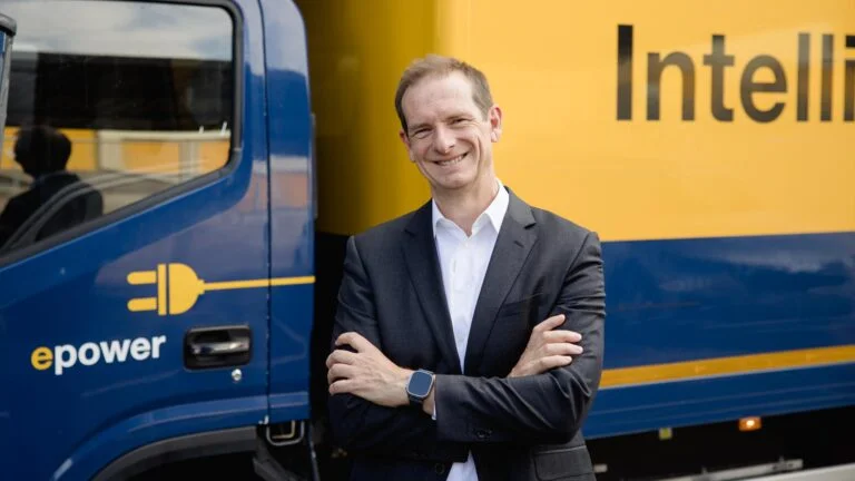 Alberto Gil Gonzalez_2_2048_1152 Alberto Gil Gonzalez vor einem blau-gelben Elektro-Lkw von DACHSER Iberia mit der Aufschrift „epower“ und angeschnittenem „Intelligent Logistics“-Schriftzug.