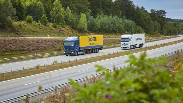 DGI_038965-JPG_2048_1152 Lkw von DACHSER Food Logistics und Frigoscandia fahren auf einer Autobahn durch eine bewaldete Landschaft.