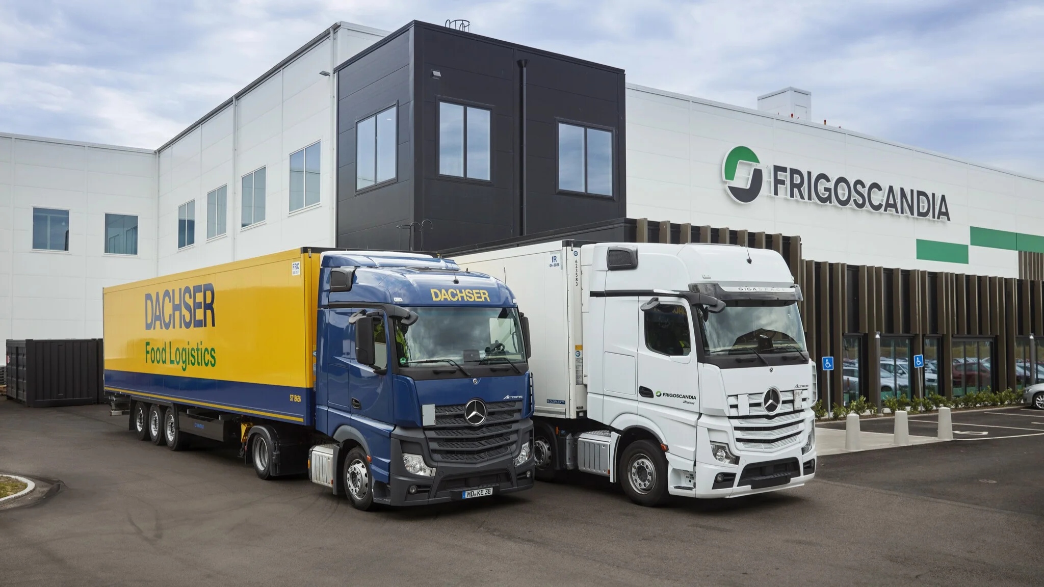 DGI_038970-JPG_2048_1152 Ein Lkw von DACHSER Food Logistics und ein Frigoscandia-Lkw stehen vor einem Frigoscandia-Logistikgebäude.